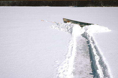 path through snow to boat on frozen lake