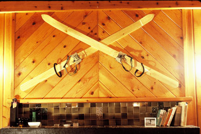 hand made skiis and brooms mounted in a cross above a fireplace