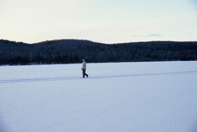figure walking across frozen lake balancing a stick